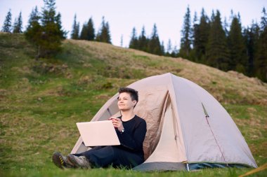 Dışarıda dizüstü bilgisayar kullanan genç bir kadın.