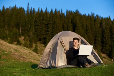 Dışarıda dizüstü bilgisayar kullanan genç bir kadın.