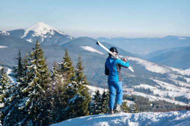bir dağın tepesinde duran kayakçı 