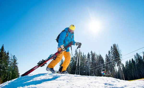 Esquiador masculino subiendo la colina nevada —  Fotos de Stock