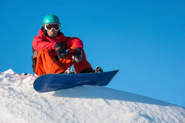Snowboarder sentado no topo da montanha — Fotografia de Stock