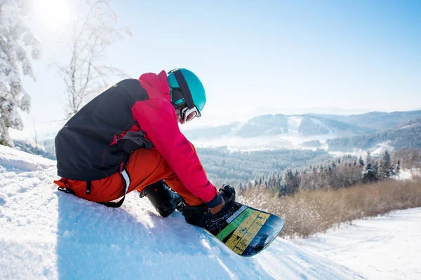 Erkek snowboard yamaçta oturan 
