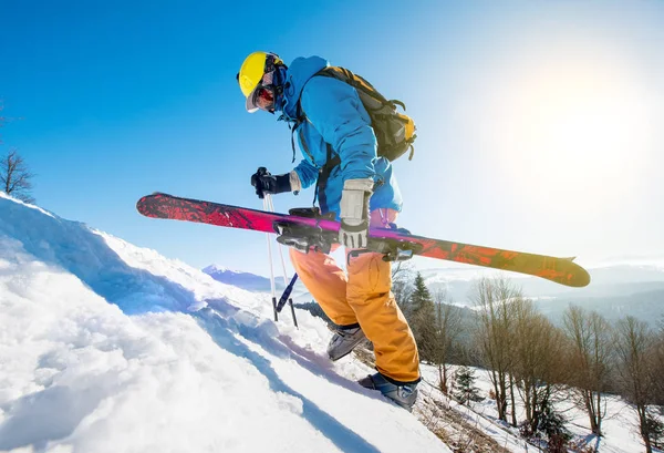 Skifahrer läuft den verschneiten Hügel hinauf — Stockfoto