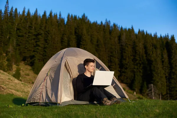 Dışarıda dizüstü bilgisayar kullanan genç bir kadın.