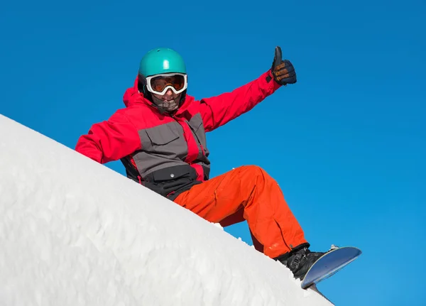 happy snowboarder sitting in the snow