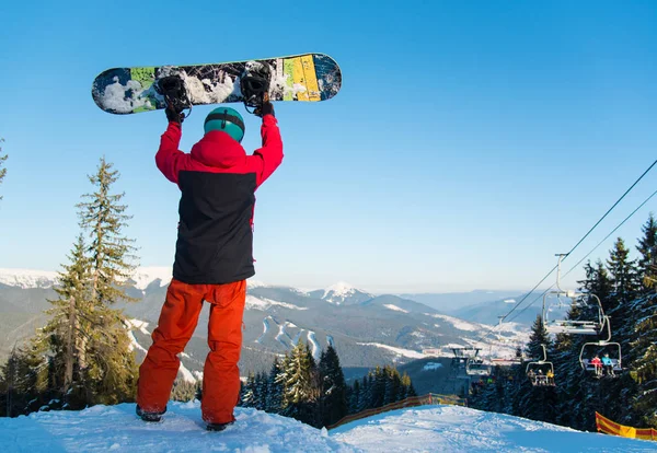 Snowboarder holding up his snowboard — Stock Photo, Image