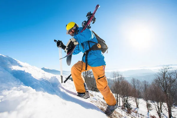 雪に覆われた丘を歩く男性スキーヤー — ストック写真