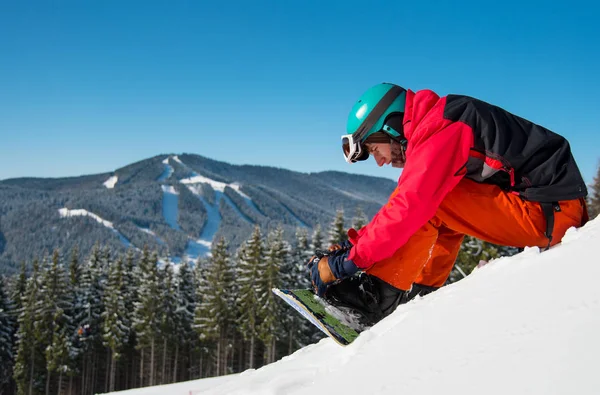 Snowboarder sitzt auf der verschneiten Piste — Stockfoto