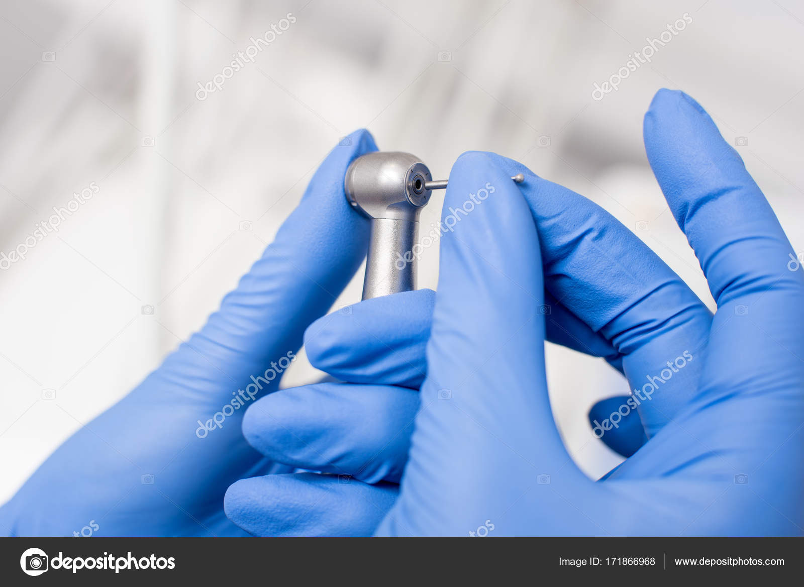 Dentist's hands with blue gloves fixing dental drill in dental office