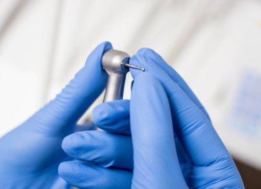 Mavi eldiven diş matkap diş ofisteki çalımakta dişçi elle. Yakın, seçici odak. Diş Hekimliği