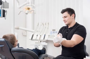 Genç çocuk hasta ile tedavi için hazırlanıyoruz, diş ofiste beyaz eldiven giyen çocuk diş hekimi. Diş Hekimliği. Diş ekipman