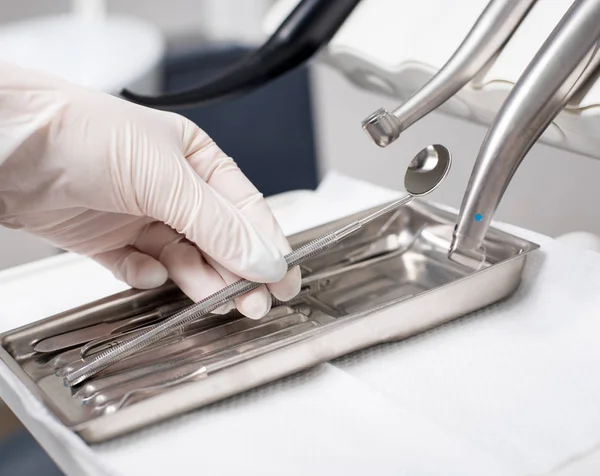 El dentista con la mano enguantada está recogiendo la herramienta dental en el consultorio dental. Primer plano, enfoque selectivo. Odontología — Foto de Stock