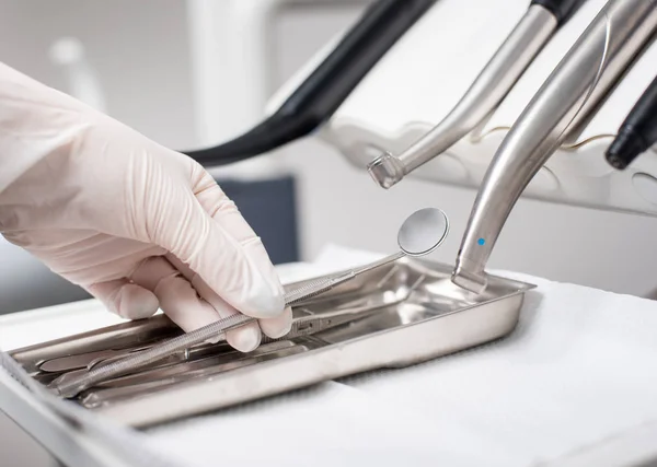 El dentista con la mano enguantada está recogiendo el espejo dental en el consultorio dental. Primer plano — Foto de Stock