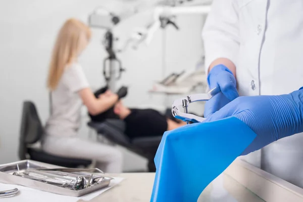 Nahaufnahme der Hände des Assistenten mit blauen Handschuhen, die mit zahnärztlichen Geräten arbeiten, auf dem unscharfen Hintergrund behandelt der Zahnarzt Patienten in der Zahnarztpraxis. Zahnmedizin — Stockfoto