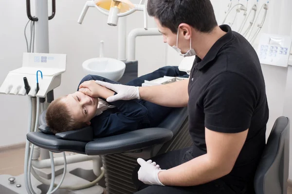 Pojke patient med tandvärk klagar till pediatric tandläkare på tandkliniken kontor. Medicin, tandvård och sjukvård koncept. Dental utrustning — Stockfoto