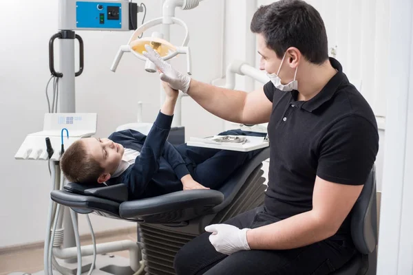 Παιδοδοντίατρος δίνει πέντε νεαρό αγόρι, να συγχαρώ τον ασθενή για μια επιτυχημένη θεραπεία στο οδοντιατρείο. Οδοντιατρική. Οδοντιατρικός εξοπλισμός — Φωτογραφία Αρχείου