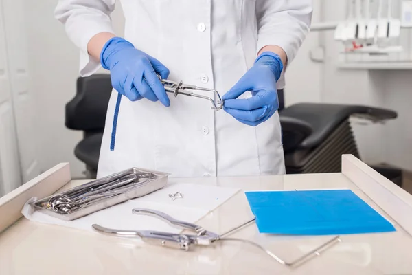 Dentista con las manos enguantadas está trabajando con el equipo dental en el consultorio dental. Primer plano — Foto de Stock