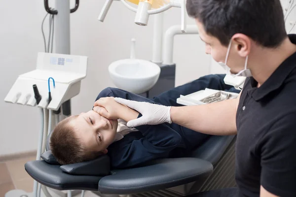 Pojke patient med tandvärk klagar till pediatric tandläkare på tandkliniken kontor. Medicin, tandvård och sjukvård koncept. Dental utrustning — Stockfoto