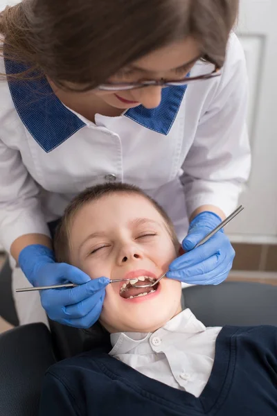 Revisión dental en el consultorio del dentista. El dentista examina los dientes de los niños en la silla del dentista. Primer plano — Foto de Stock