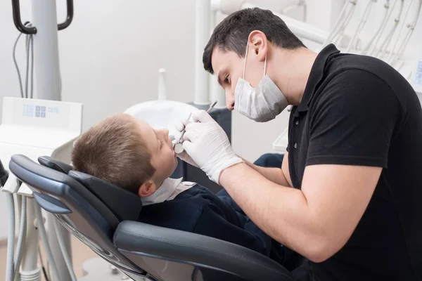 Pediatric tandläkare undersöker tänder av pojken patient i tandvårdsklinik med dental verktyg - spegel och sond. Tandvård — Stockfoto