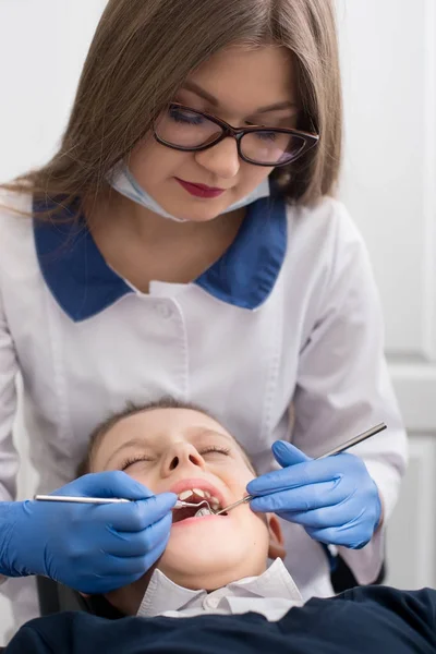 Dentiste femme en gants traite les dents garçon de l'étude. Médecine, stomatologie, technologie et concept de soins de santé — Photo