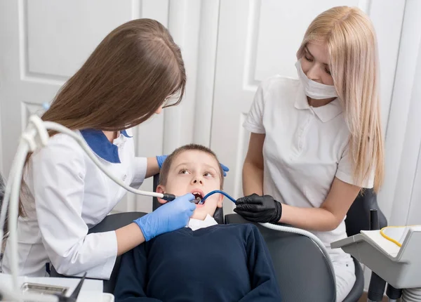 Jeunes dentistes féminines examinant et travaillant sur un patient garçon. Médecine, stomatologie, technologie et concept de soins de santé — Photo