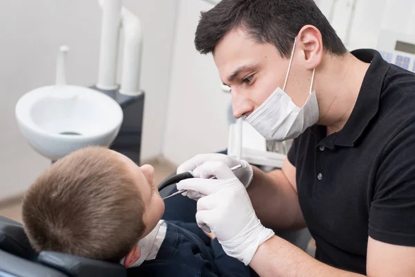 Pediatric tandläkare undersöker tänder av pojken patient i tandvårdsklinik med dental verktyg - spegel och sond. Tandvård — Stockfoto