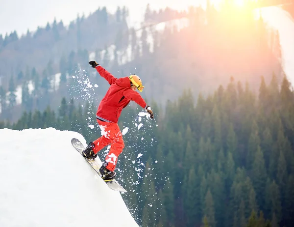 Сноубордист прыгает со снежного холма — стоковое фото