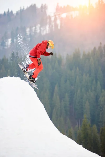 Snowboarder springt von verschneiter Schanze — Stockfoto