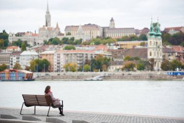 Yalnız bir kız Budapeşte Nehri yakınında çıkabilir ve Buda yan Budapeşte Buda Castle, St. Matthias ve Fisherman's Bastion görünümünü bir bankta oturur. Arka plan bulanık. Arkadan Görünüm
