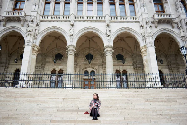 Doce menina sentada nos degraus do Palácio do Parlamento em Budapeste, Hungria. Outono — Fotografia de Stock