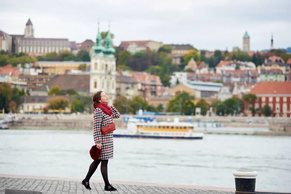 Mulher terno goza de solitário aterro de Budapeste com visão turva do lado Buda de Budapeste com o Castelo de Buda, St. Matthias e Bastião dos Pescadores . — Fotografia de Stock