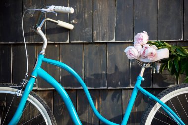 Mavi vintage Bisiklet yakın karanlık duvar zemin üzerine hafifçe pembe peonies buket ile çekim
