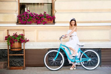 Şehir sokak bisiklet üzerinde otururken gülümseyen güzel mutlu genç kadın 