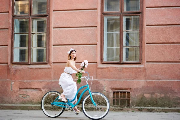 Χαμογελώντας Ελκυστική Γυναίκα Στην Λευκή Φόρεμα Κρατώντας Λουλούδια Και Ιππασία — Φωτογραφία Αρχείου