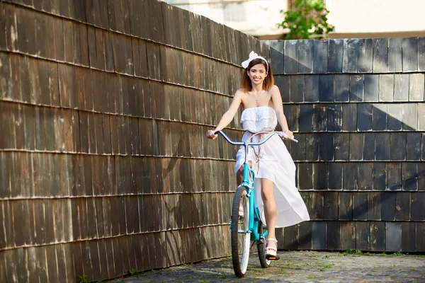 화창한 어두운 포장된 거리에 빈티지 자전거를 드레스에 매력적인 여자를 — 스톡 사진