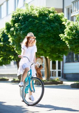 Şehrin bir güneşli yaz gününde sokak üzerinde genç kadın bisikletçi.