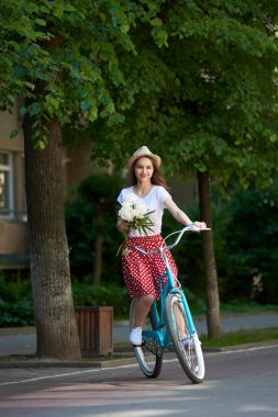 Lekeli ve mavi bir retro bisikleti peonies ile kafasına bir şapka ile kırmızı etekli ihale genç kadın. 