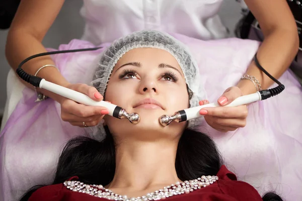 Una joven paciente está recibiendo masaje facial en un salón de belleza. Cosmetología y rutina de cuidado de la piel . —  Fotos de Stock