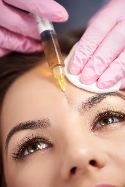 Makró fotózás nő gyönyörű szemek kap injekció arcú nő homlokán. Műanyag arc esztétikai sebészet szépségcentrum. — Stock Fotó
