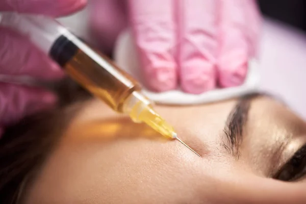 Closeup injekční stříkačka provádí docela klientku salonu krásy. Kosmetika a pleť péče rutina. — Stock fotografie