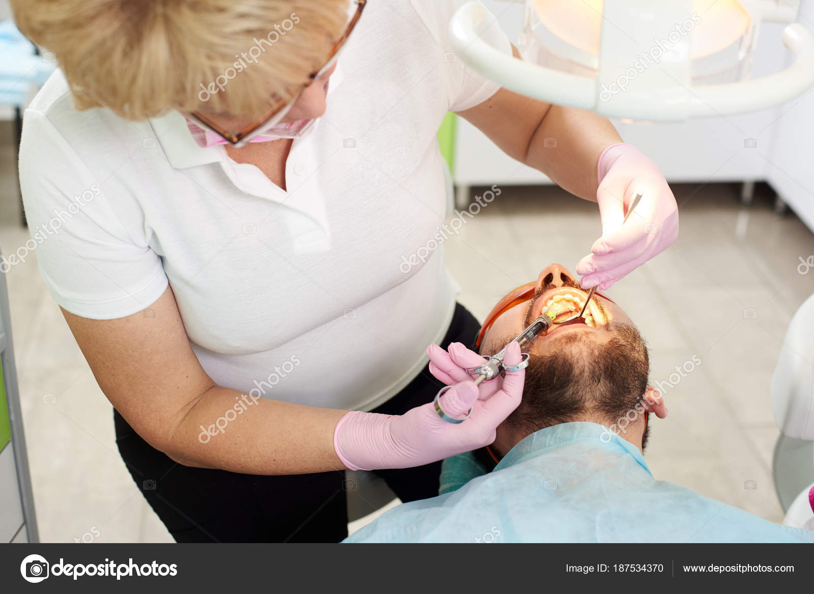 Dentist woman makes anesthetizing injection within a patient's mouth. Injection techniques to