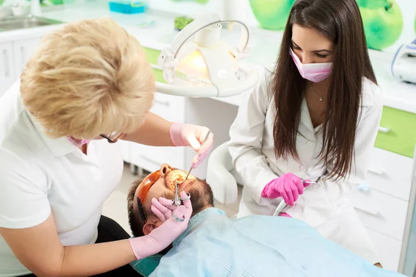 Stomatologin injizierte Anästhesie an jungen Mann vor Zahnbehandlung mit ihrem Assistenten in moderner Klinik — Stockfoto