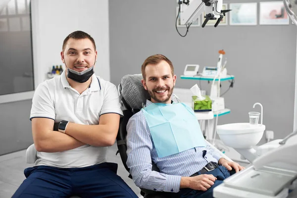 医生坐在牙科椅上满意的病人旁边。现代牙科与新技术的应用 — 图库照片
