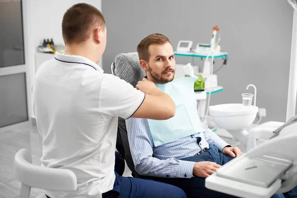 歯科医は、歯科用の椅子の検査のため患者を準備します。革新的な技術とモダンな歯科医院。患者を見てカメラ — ストック写真