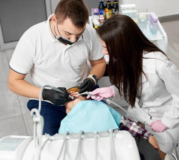 Zahnarzt-Rüde mit Assistentin behandelt süße Jungenzähne in moderner Klinik — Stockfoto