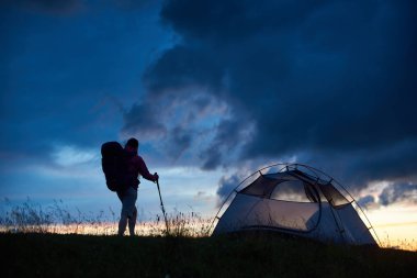 Çadır campisite doğa sahne akşam manzara özgürlük başarı başarı liderlik hiking günbatımı boşaltmak kamp üzerinde bir dağın tepesinde yakın duran bir backpacker kadeh.
