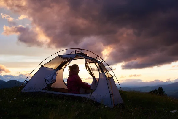 Turista sentada en su tienda de campaña en la cima de una montaña durante el impresionante atardecer copyspace camping senderismo viajar turismo estilo de vida paisaje natural paisaje noche relajación . — Foto de Stock