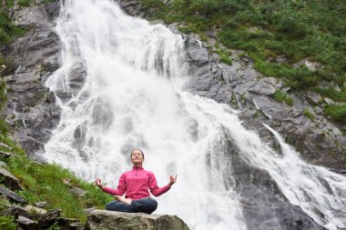 Meditasyon, şelale Balea Fagarash dağlarda karşı rahat rahatlatıcı pratik yoga, genç erkek. Dağlarda kayalık şelale.