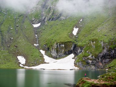 Yüce Dağları sis ve gölün dibinde, Transilvanya, Romanya ile kaplıdır. Uzaktan görkemli sahne hoşlanan bir turist kız görebilirsiniz